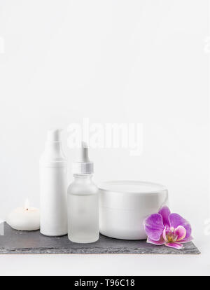 Anderes Material, Form und Größe Kosmetik Creme, Öl behälter auf weißem Hintergrund stehen auf schwarzen Stein Base, Pink Orchid Blossom. Stockfoto