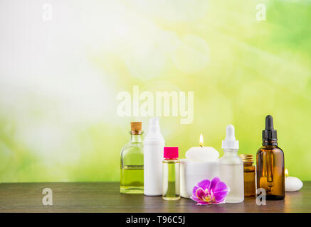 Komposition mit viel unterschiedlicher Größe, Form und Material Beauty Kosmetik Produkte Flaschen Anordnung auf hölzernen Tisch mit grünen bokeh Studio hinterg Stockfoto