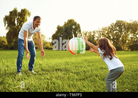 Vater mit einer kleinen Tochter spielen mit einem Ball in der Natur. Stockfoto