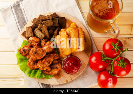 Lecker gebratenes Huhn mit Käse Sticks, Zwieback, Soße und kaltes Bier auf Holzbrett. Straße fast food festivel Konzept. Stockfoto