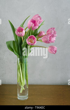 Blumenstrauß aus rosa Tulpen in der Vase vor grauen Wand Stockfoto
