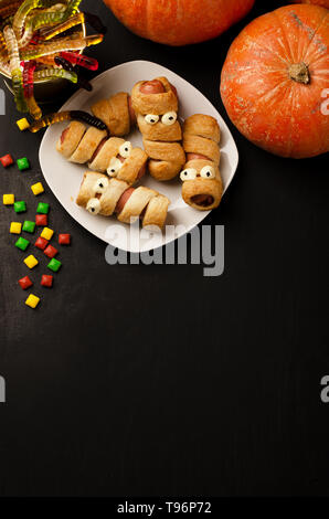 Beängstigend wurst Mumien im Teig mit lustigen Augen am Tisch und spase für Text. Halloween Essen. Stockfoto