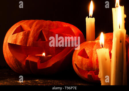 Orange Kürbisse Jack-o'-Lantern als Kopf mit brennenden Kerzen auf schwarzem Hintergrund Stockfoto