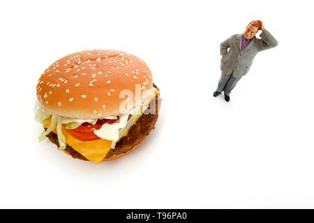 Symbol Bild Übergewicht, ungesunde Ernährung, nachdenkliche Figur vor der Cheeseburger, Deutschland Stockfoto