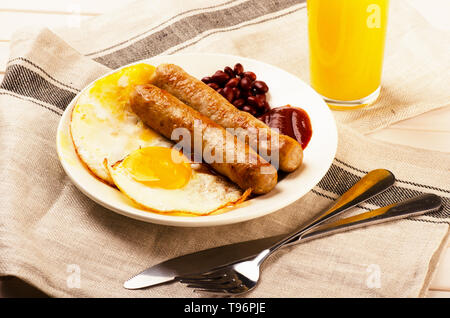 Gegrillte Würstchen mit Sauce Ketchup, orange juise und Rührei Stockfoto