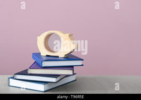 Piggy Bank und Stapel von Büchern auf dem Tisch. Konzept der Einsparungen für Bildung Stockfoto