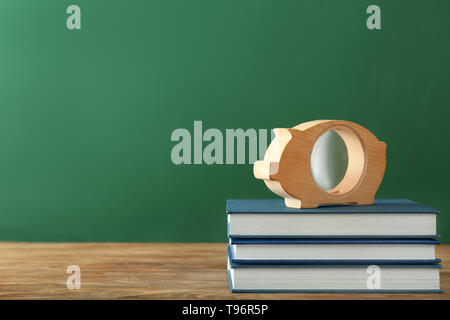 Piggy Bank und Stapel von Büchern auf dem Tisch. Konzept der Einsparungen für Bildung Stockfoto