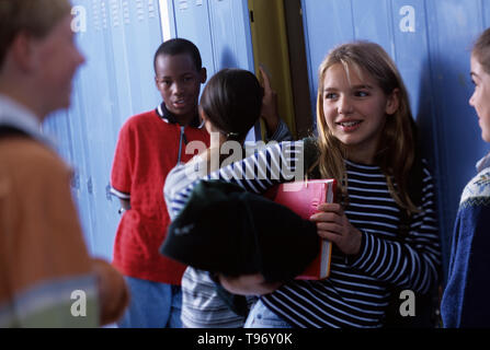 Gruppe von Freunden sprechen, nachdem der Klasse in der Nähe von Schule Schließfächer im Flur Stockfoto