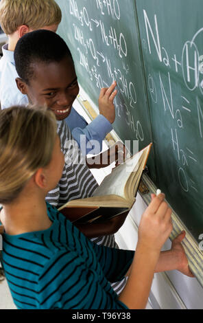 Drei Schüler Abschluss einer Wissenschaft Zuordnung auf dem schulzimmer Tafel Stockfoto