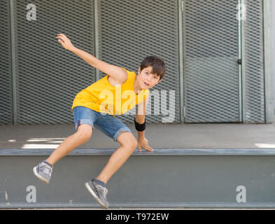 Vorderansicht eines lächelnden Jungen springen über eine metallische Zaun, während Sie die Kamera an einem hellen Tag Stockfoto