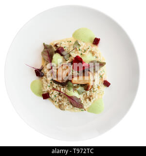 Risotto mit gebratenen Steinpilzen auf weiße Platte, auf weißem Hintergrund mit Freistellungspfad isoliert Stockfoto