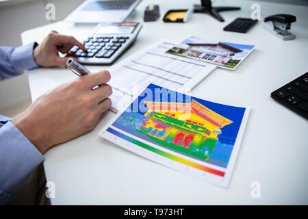 Nahaufnahme der Person Hand Berechnung von Temperatur mit dem Rechner auf dem Schreibtisch Stockfoto