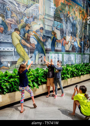 Während ein Freund einen ein Foto findet, Kinder imitieren die Posen der Automobilindustrie Arbeiter in Diego Rivera's berühmten Ford Motor Company dargestellt Fresken auf der Detroit Institut für Kunst. Stockfoto