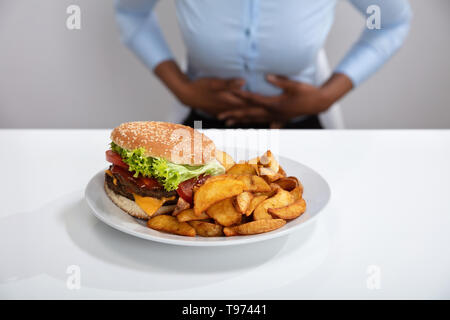 Junge Frau mit Magenschmerzen Beim Frühstück Stockfoto