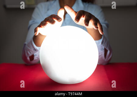 Nahaufnahme der Wahrsager Hand über die glühende Glaskugel Rot Schreibtisch Stockfoto