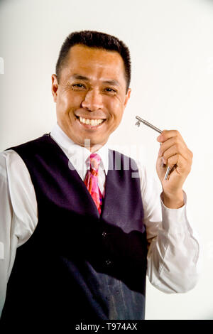 Ein lächelndes Asian American Railroad service Attendant zeigt seine Sicherheitsschlüssel auf der Los Angeles train Yards. MODEL RELEASE Stockfoto
