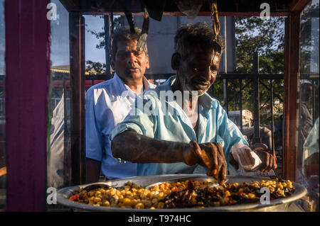 Anbieter serviert Snacks, ein Kunde an einem Fast Food stall, Kandy, Sri Lanka Stockfoto