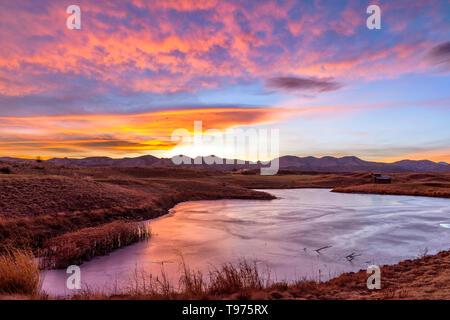 Sonnenuntergang gefrorenen Bergsee - eine bunte winter Sonnenuntergang an einem zugefrorenen Bergsee. Bear Creek Park, Denver-Lakewood, Colorado, USA. Stockfoto