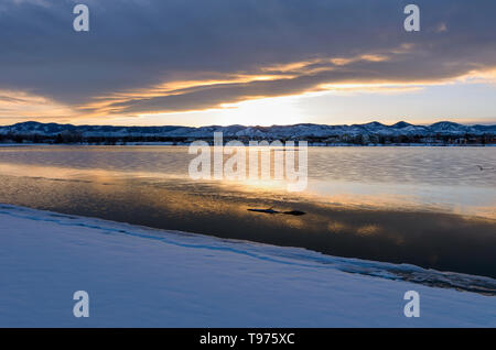 Stürmische Winter Lake - ein Sonnenuntergang von wintersturm Wolken über Schnee und Eis berg Stadt See bedeckt. Johnson Reservoir, Littleton, CO, USA. Stockfoto