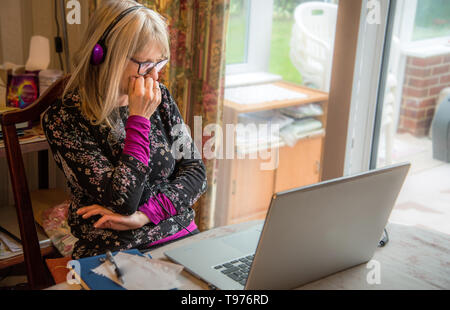 Aufzeichnen von Notizen während des Abhörens einer Web-basierten Seminar live online über Kopfhörer ausgestrahlt wird. Stockfoto