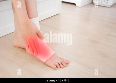 Nahaufnahme von einem Fuß mit Gaze Elastische Bandage. Asiatische Frau Knöchelverletzung Runner. Hände auf verletzte Beine und Füße mit roten Fleck auf Schmerz Bereich sitzen. Stockfoto