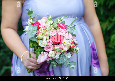 Kaukasische weiblichen Gast oder Brautjungfer das Tragen eines flieder Sommer Kleid zeigt einen schönen Baby bump und halten einen delikaten Bouquet in freier Form Stockfoto