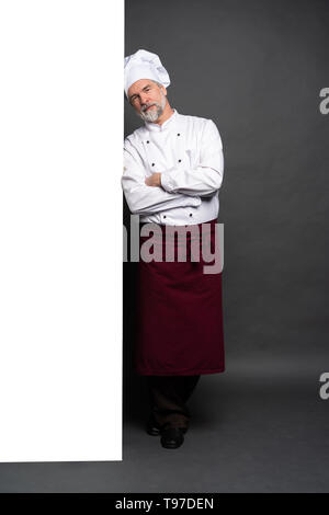 Full Length Portrait Of Happy Chef Koch Übersicht copyspace auf den Handflächen auf schwarzem Hintergrund isoliert. Stockfoto