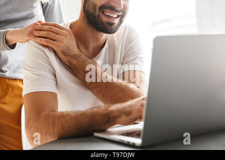 Zugeschnittenes Bild erstaunlich glückliches junges Paar in der Küche mit Laptop Computer sitzen. Stockfoto