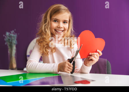 Süße kleine Mädchen ein Herz aus Papier auf dem Tisch Stockfoto