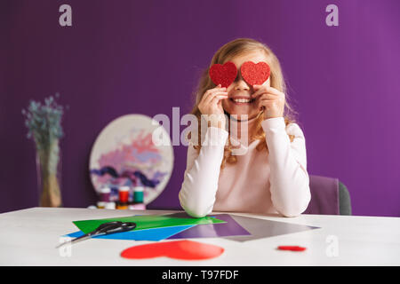 Süße kleine Mädchen ein Herz aus Papier auf dem Tisch Stockfoto