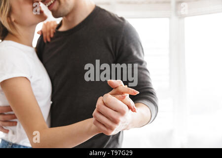 Portrait von europäischen Paar umarmen und tanzen zusammen, während in hellen Zimmer zu Hause ausruhen Stockfoto