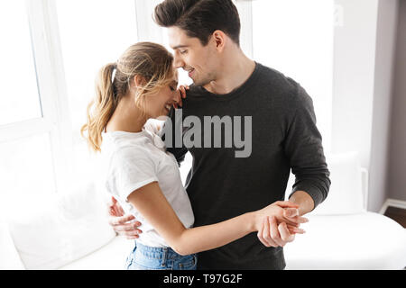 Portrait von glückliches Paar umarmen und tanzen zusammen, während in hellen Zimmer zu Hause ausruhen Stockfoto