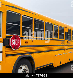 Platz Seitenansicht eines School Bus auf einer Straße, die durch verschneite Häuser im Winter Stockfoto