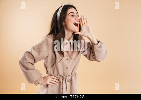 Bild des schönen neugierige junge hübsche Frau über beigen Hintergrund Wand schreien isoliert posieren. Stockfoto