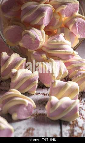 Rosa Marshmallows mit weißen Locken genügend Schlaf mit einem transparenten Behälter an der alten hölzernen Hintergrund Stockfoto