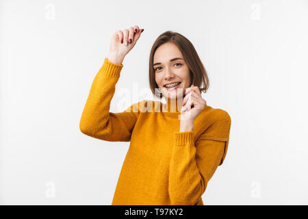 Schöne junge Mädchen mit Zahnspangen, die auf weißem Hintergrund, Erfolg feiern. Stockfoto