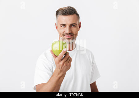 Bild der glücklichen Mann 30 s mit Borsten auf Kamera posieren und halten Grüner Apfel in der Hand auf weißem Hintergrund Stockfoto