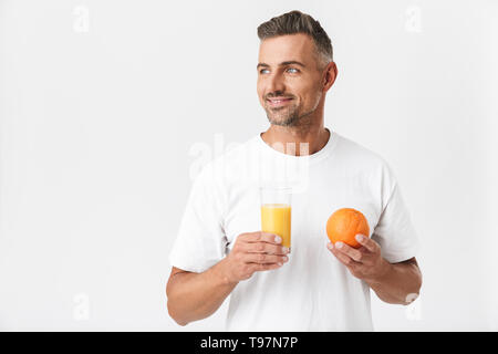 Bild Der unrasierte Mann 30 s mit Borsten legere t-shirt Holding Glas Saft und Obst orange auf weißem Hintergrund Stockfoto