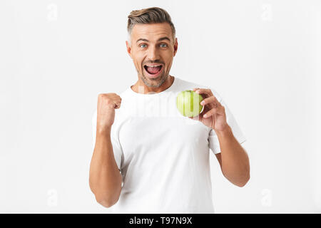 Portrait von optimistischen Mann 30 s in Borsten in casual t-shirt auf Kamera posieren und halten Grüner Apfel in der Hand auf weißem Hintergrund Stockfoto