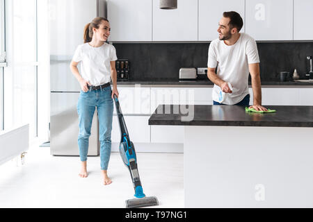 Glückliches junges paar Reinigung Küche zusammen, lächelnd Stockfoto
