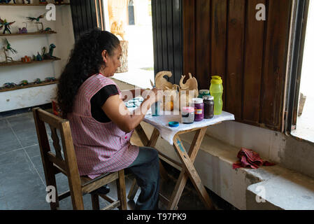 Mexikanische Frau malt alebrijes (Skulpturen aus Holz). San Martín Tilcajete, Oaxaca, Mexiko. Apr 2019 Stockfoto