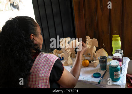 Mexikanische Frau malt alebrijes (Skulpturen aus Holz). San Martín Tilcajete, Oaxaca, Mexiko. Apr 2019 Stockfoto