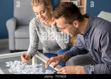 Junges Paar Montage Puzzle auf Glas Tisch zu Hause Stockfoto