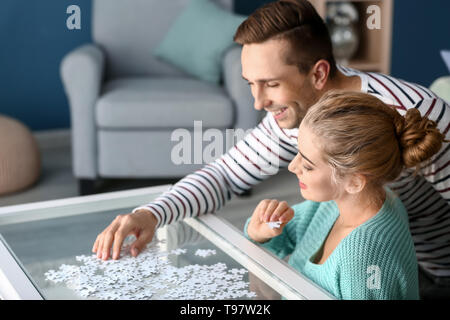 Junges Paar Montage Puzzle auf Glas Tisch zu Hause Stockfoto
