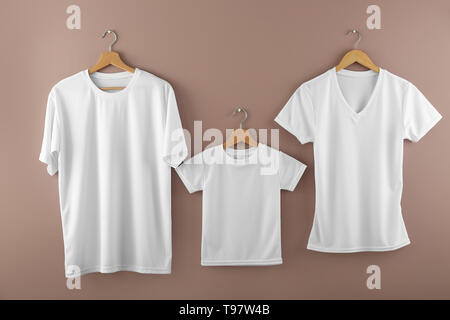 Kleiderbügel mit leeren weißen T-Shirts auf farbigen Hintergrund Stockfoto
