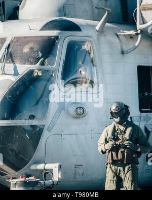 190511-M-HB 658-0028 PAZIFISCHER OZEAN (11. Mai 2019) eine US Marine Corps CH-53E Super Stallion Crew Chief mit Marine Medium Tiltrotor Squadron (VMM) 163 (verstärkt), 11 Marine Expeditionary Unit (MEU), steht neben einem Flugzeug an Bord der San Antonio-Klasse amphibious Transport dock Schiff USS John Murtha (LPD S. 26). Die Marinesoldaten und Matrosen der 11 MEU führen routinemäßige Vorgänge als Teil der Boxer Amphibious Ready Gruppe. (U.S. Marine Corps Foto: Staff Sgt. Donald Holbert) Stockfoto