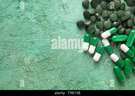 Spirulina Tabletten und Kapseln auf farbigen Hintergrund Stockfoto