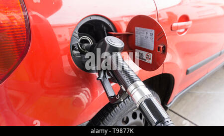 Ein rotes Auto ist an einer Tankstelle und ist mit Diesel betankt. Nahaufnahme der Tap und dem Tank. Stockfoto
