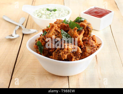 Pakoda, einem traditionellen, beliebten, köstlich und eine indisch vegetarisch hausgemachte Snacks, wird von deep-frying Portionen Kichererbsenmehl Teig. Stockfoto