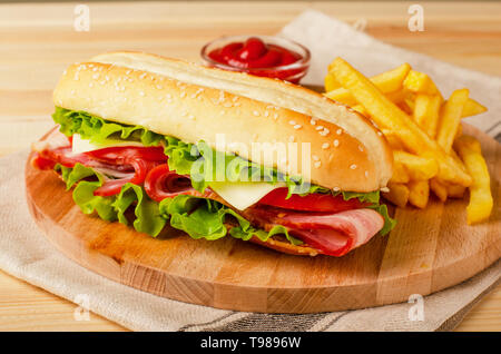 Submarine Sandwich mit Schinken, Käse, Tomaten und Salat auf Holz- Hintergrund Stockfoto